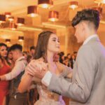 A couple dancing gracefully at a formal party with elegant lighting.